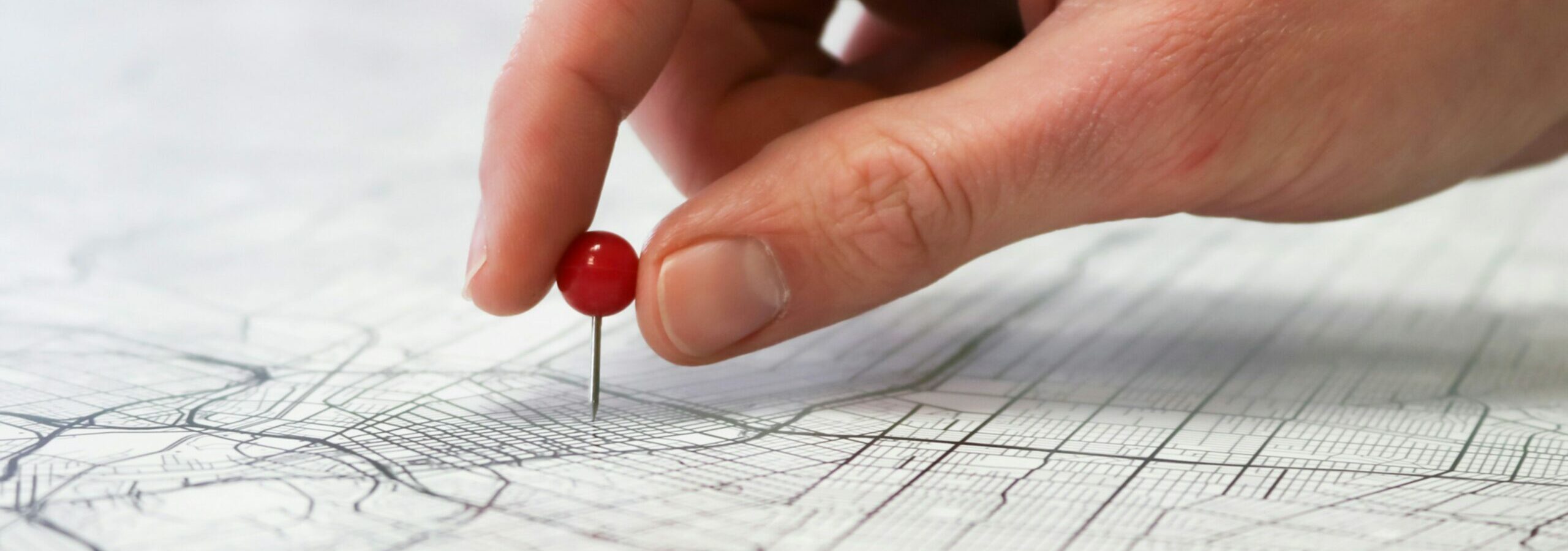 Une main mettant des épingles sur une carte