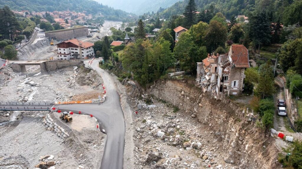 Vue aérienne de dégats sur la commune de la Vésubie. On voit des maisons effondrées et le chenal d'écoulement du cours d'eau.